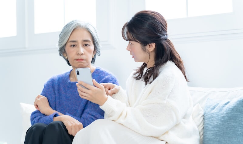 携帯を訝しげに見る親と娘